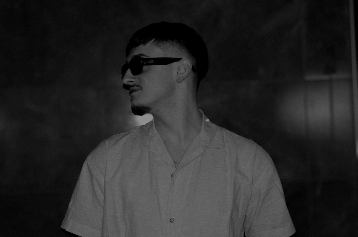 DJ NOIR im Profil mit Sonnenbrille, Schwarz-Weiß-Porträt vor dunkler Wand